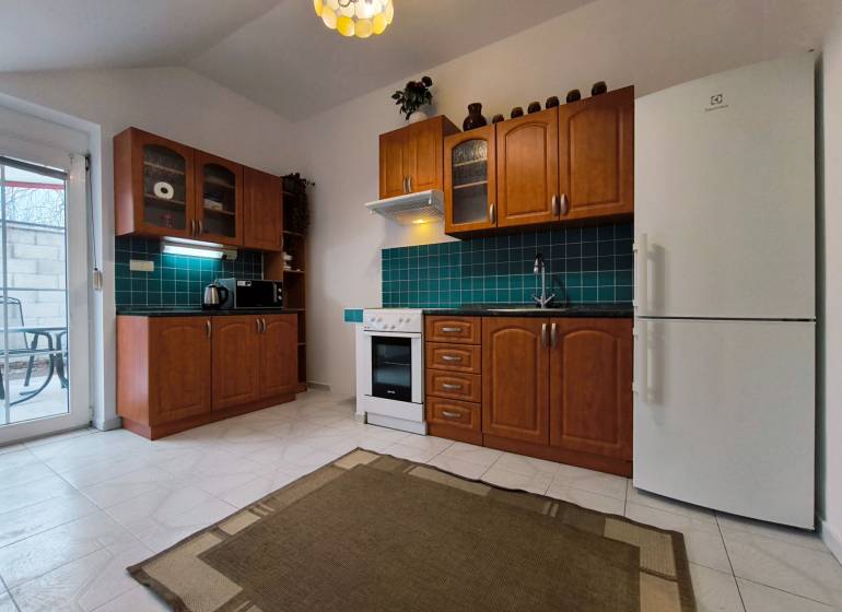 A kitchen with wooden cabinets and green tiles in a family house.
