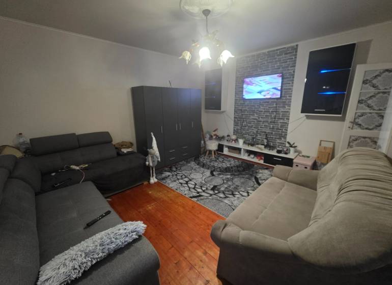 Living room with two sofas, a TV on the wall, and a wooden decor floor.