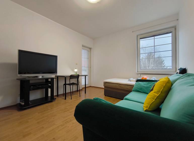 Living room in a family house with a sofa, television, table, and wooden decor flooring.