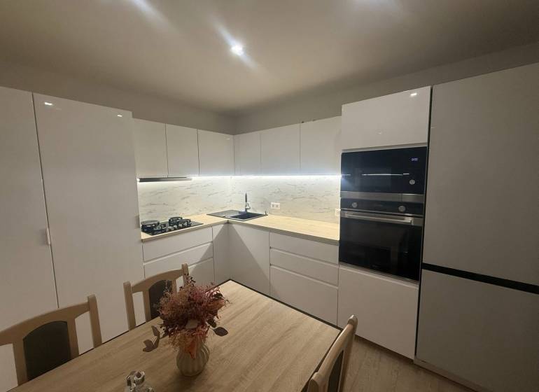 Modern kitchen in a 3-room apartment with white cabinets and marble tiles.