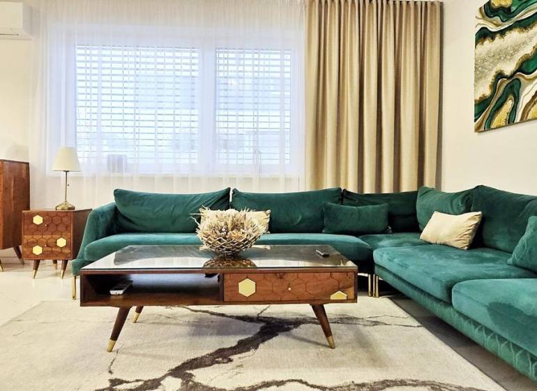 Family house with a green-toned sofa, wooden furniture, and art on the wall.