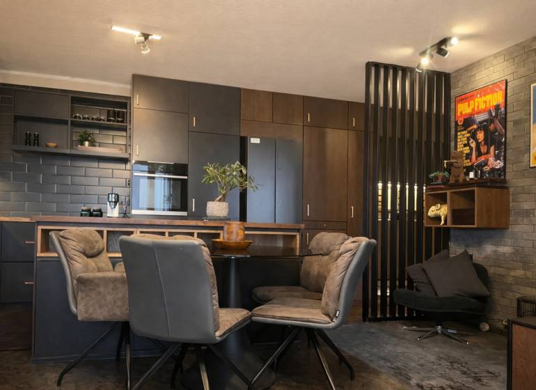 A kitchen in a 2-room apartment with dark cabinets and decorative posters on the wall.