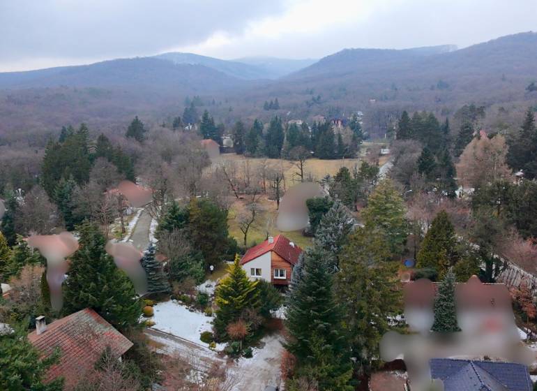 A wooded landscape with cottages in Modra surrounded by mountains and trees.