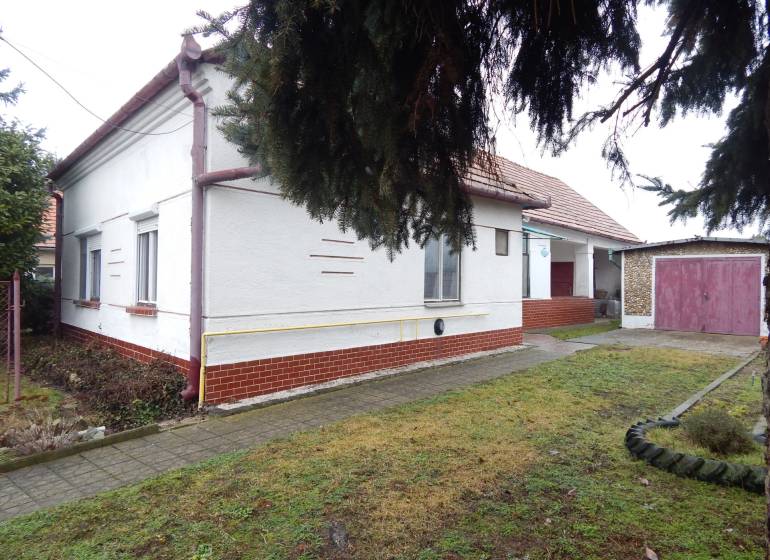 A family house in Kravany nad Dunajom with a garage, next to it a sidewalk and a grassy area.