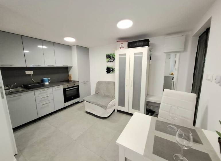 A kitchen in a cottage, with a dining table and gray kitchen cabinets.