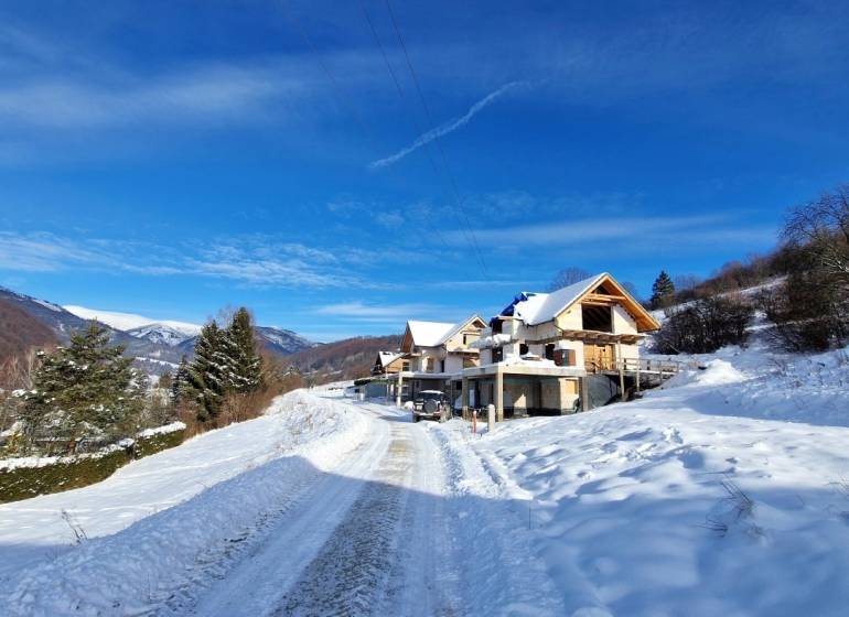 A snowy landscape and houses under construction on plots in Mýto pod Ďumbierom.