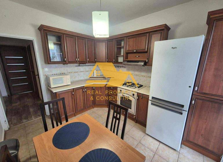 A kitchen with dark wood decor, a stove, and a refrigerator in a 3-room apartment.