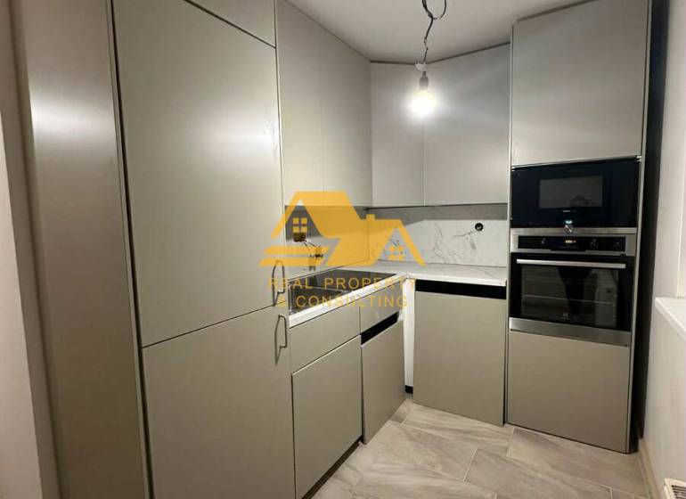 A kitchen in a 2-room apartment with modern cabinets and appliances.