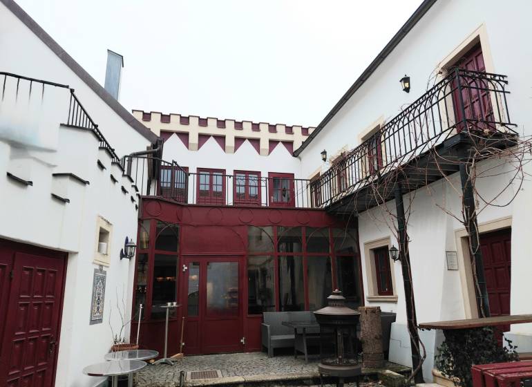The courtyard of the offices on Hauptstraße in Eisenstadt with red doors and a balcony.