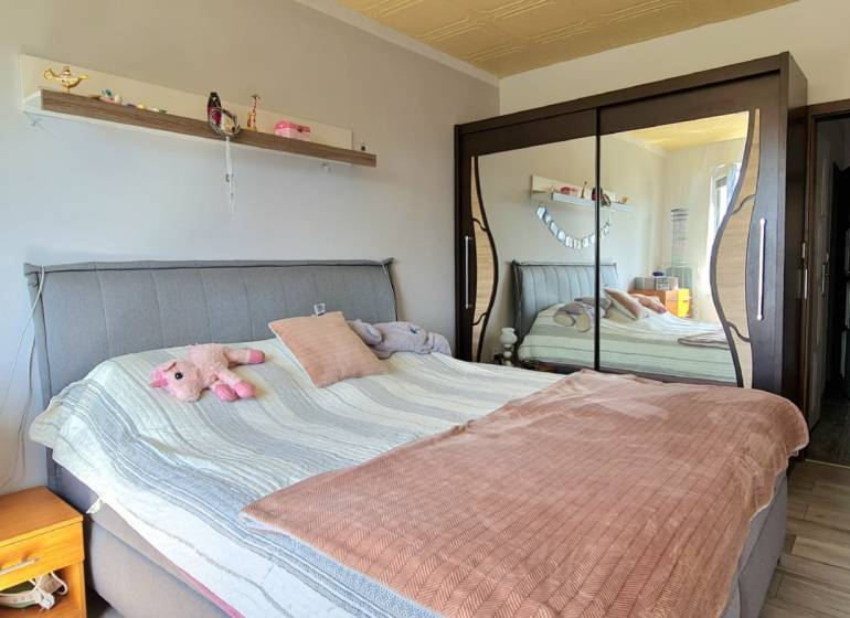 A bedroom in a two-room apartment with a mirrored wardrobe and an upholstered bed.