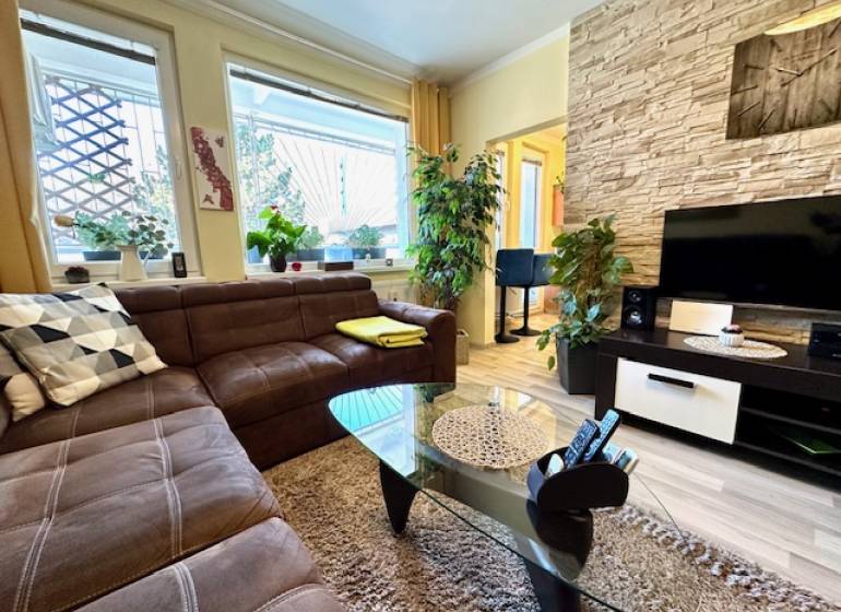 Living room in a one-room apartment with a brown sofa and a wooden decor floor.