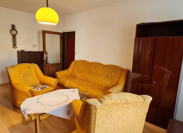 A living room in a three-room apartment with brown furniture and yellow sofas.