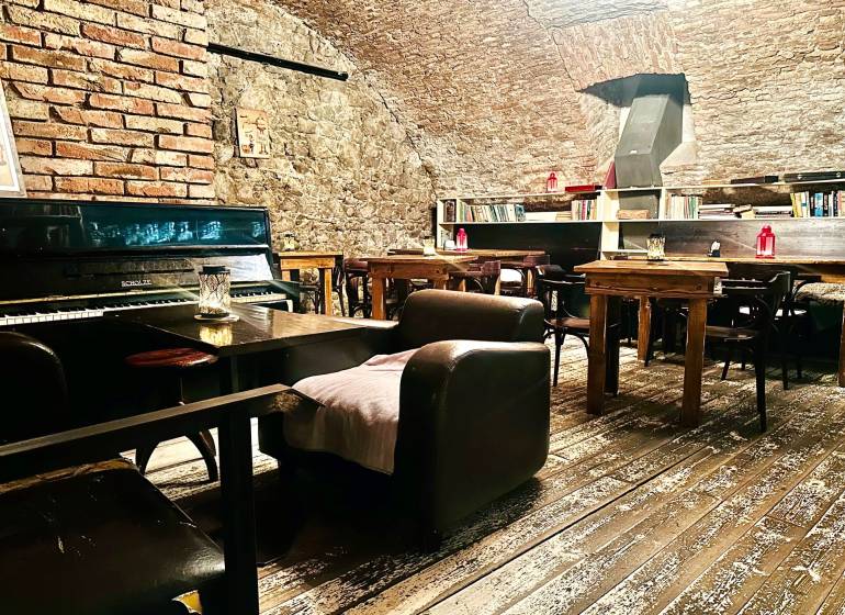 Interior with brick walls, piano, and bookshelf, wooden decor flooring, gastro spaces.