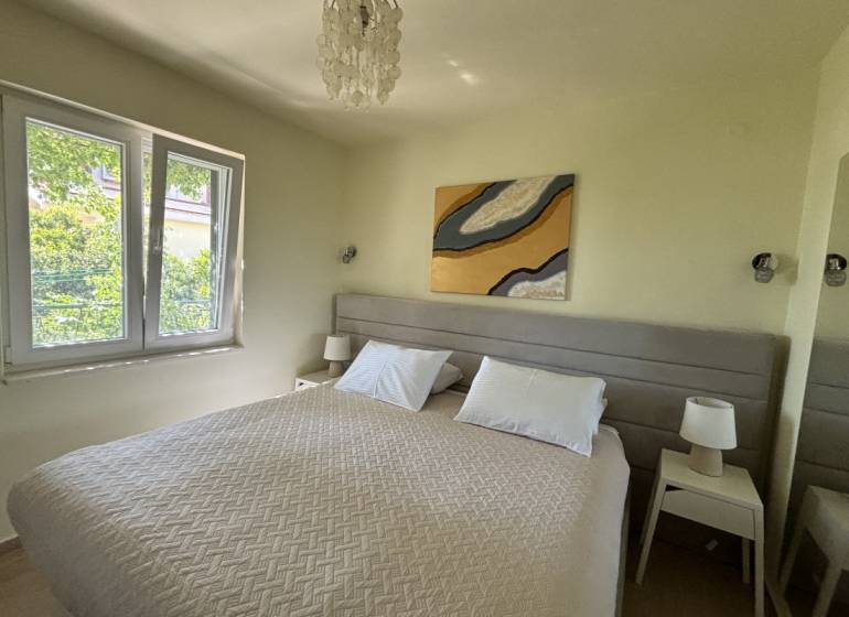 Bedroom in a family house with a double bed, tables with lamps, large window.