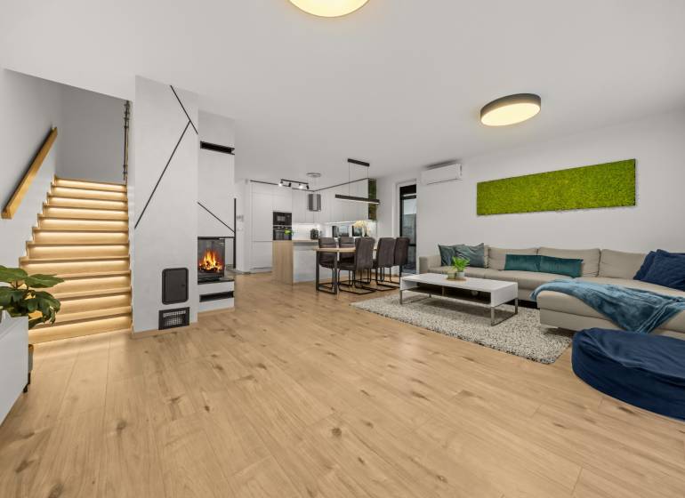 Living room of a 4-room apartment with a wood-patterned floor, fireplace, and modern staircase.