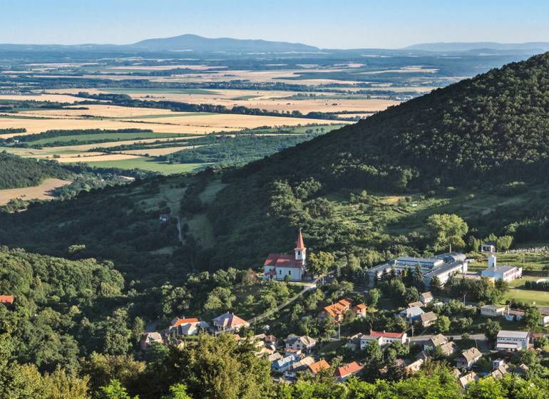 Panoramic view of a village in a valley, surrounded by forests and fields. Land suitable for living.