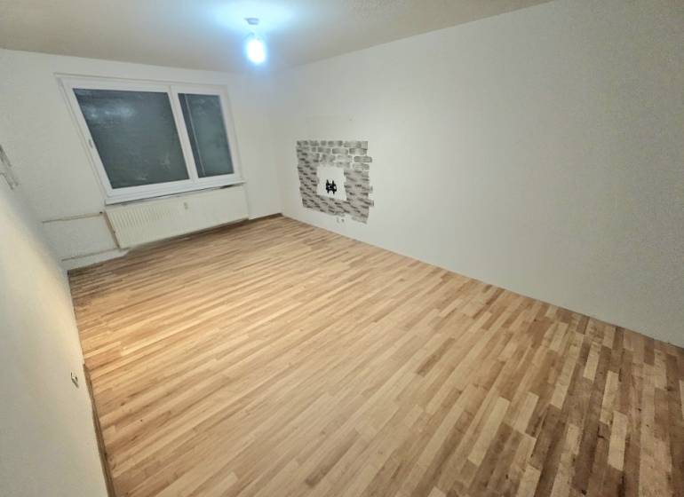 Living room with wood-patterned flooring and a window in a 3-room apartment.