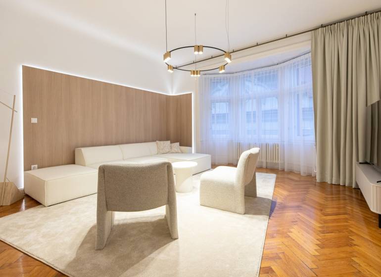 Living room in a three-room apartment with a wooden decor floor, beige carpet, and seating.