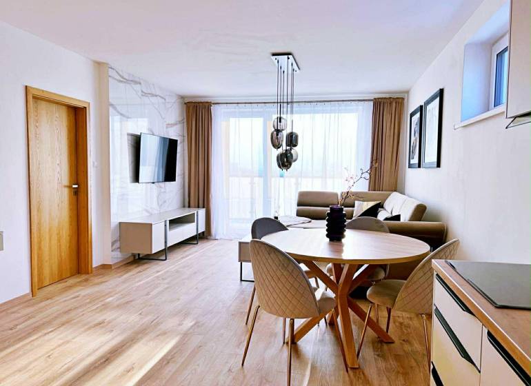 Living room in a three-room apartment with light furniture and a wooden decor floor.