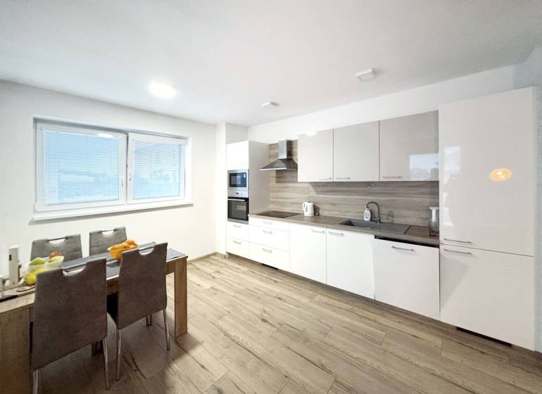 A kitchen in a 3-room apartment with a modern kitchen unit and a floor with a wooden decor.