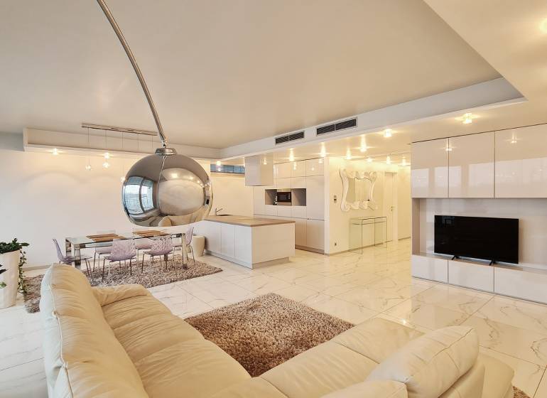 Interior of a 3-room apartment with an open kitchen and a white sofa.