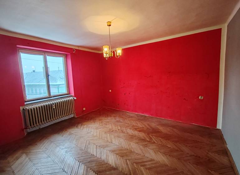 A room with red walls and a wooden decor floor in a 2-room apartment.