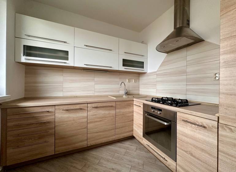 A kitchen in a 3-room apartment with a wooden decor floor and modern appliances.