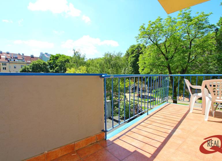 Balcony of a 3-room apartment with a view of greenery and a children's playground.