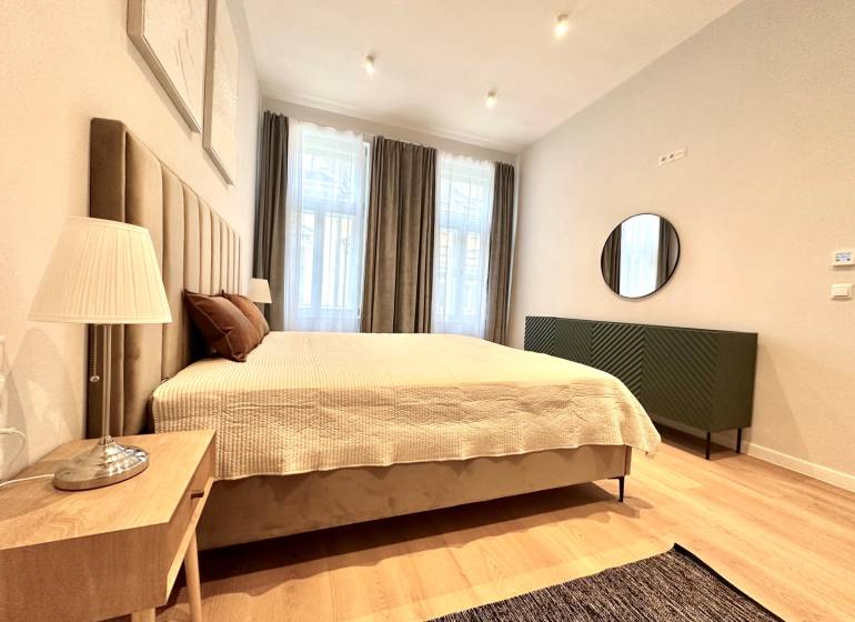 Bedroom in a 2-room apartment with a large bed, lamp, and floor with wood decor.