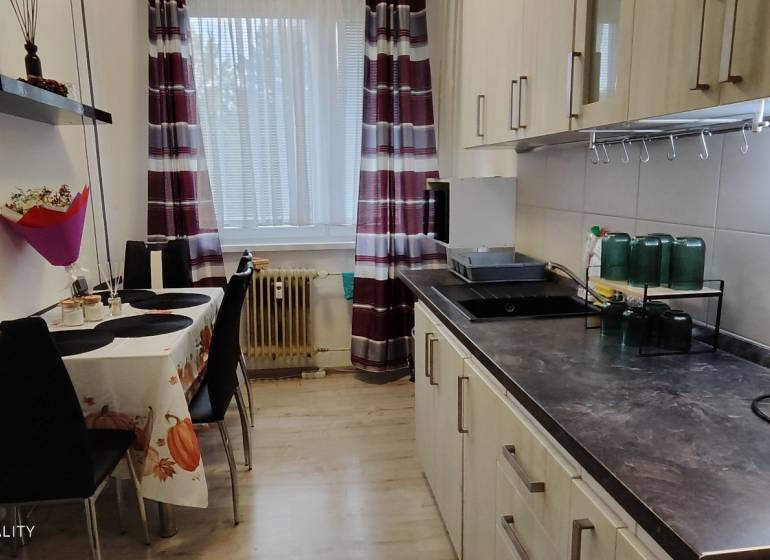 A kitchen in a 3-room apartment with a wooden decor floor and a dining table.