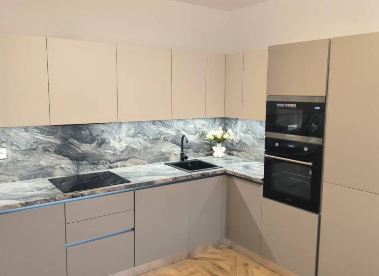 Kitchen in a 4-room apartment with a kitchen unit, appliances, and flooring with a wood decor.