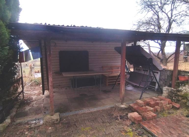 A shelter from gardens in Nové Mesto nad Váhom with wooden pillars and stored bricks.