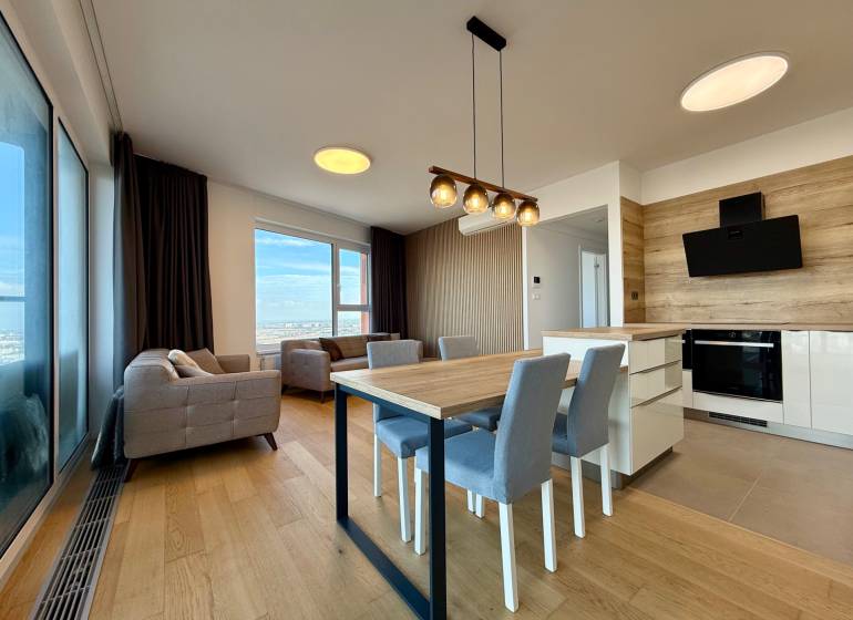 Living room with a kitchenette, equipped with sofas, a dining table, and a floor with a wooden decor.