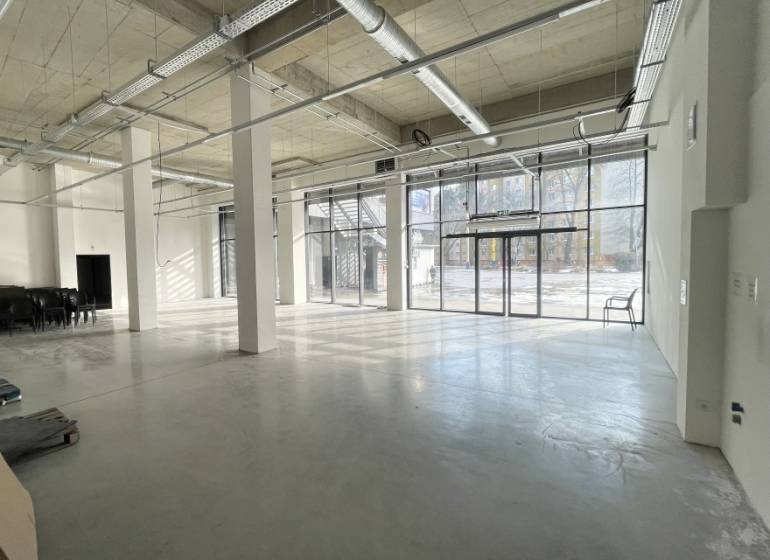 Spacious commercial spaces with large windows, concrete flooring, and light strips.