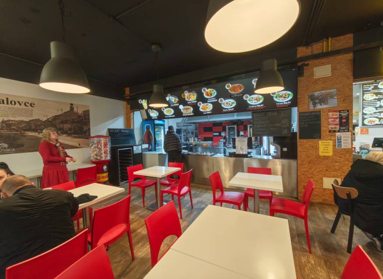 Gastro premises with wooden decor flooring, red chairs, and lights.