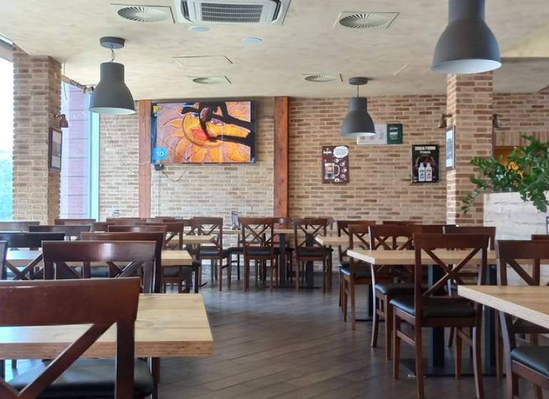Interior of a gastro space with brick walls, a wooden decor floor, and hanging lamps.