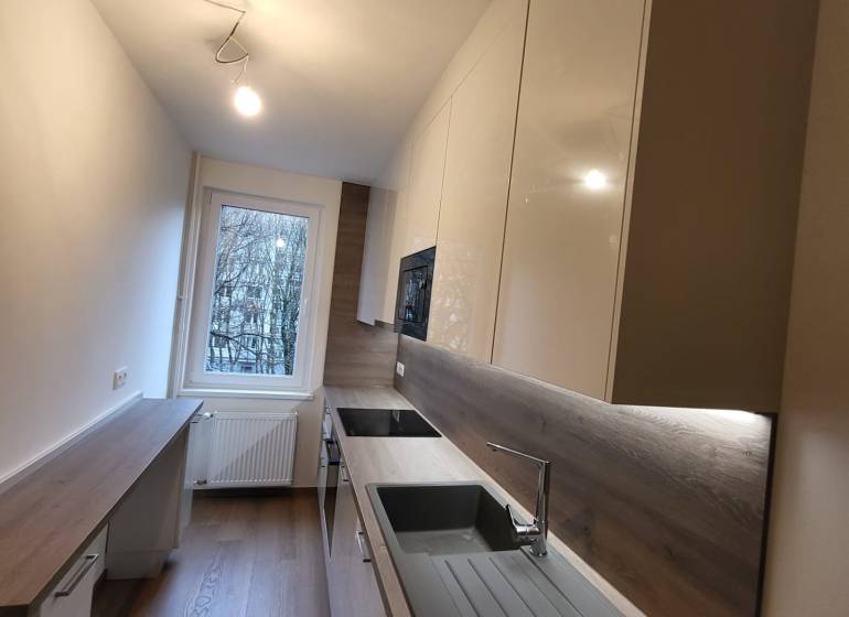 A new kitchen in a 2-room apartment with a wood-patterned floor and modern equipment.