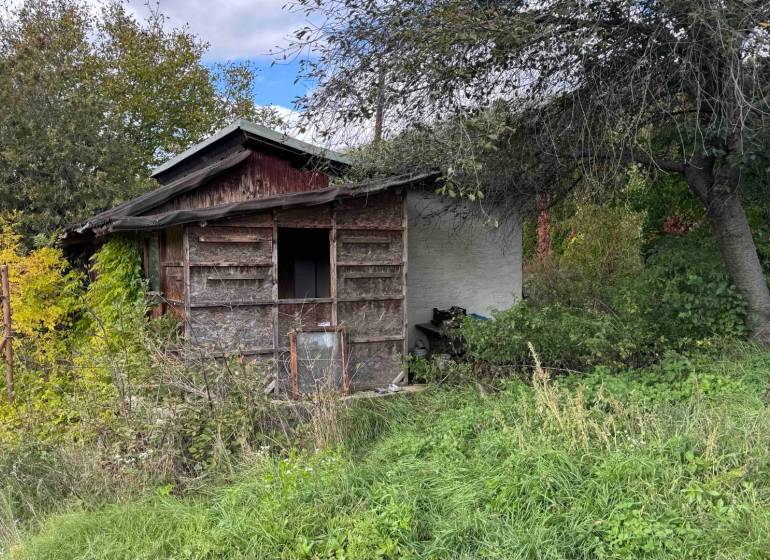 An abandoned cottage in Hlohovec surrounded by dense vegetation and neglected surroundings.
