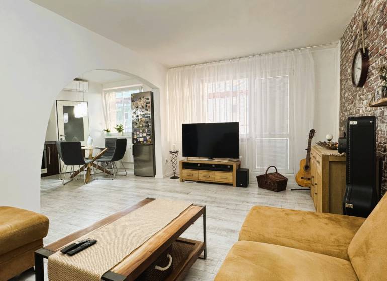 Living room in a three-room apartment with a wooden decor floor and a brick wall.