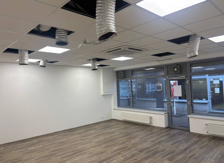 Commercial premises with wood-patterned flooring and ceiling ventilation.