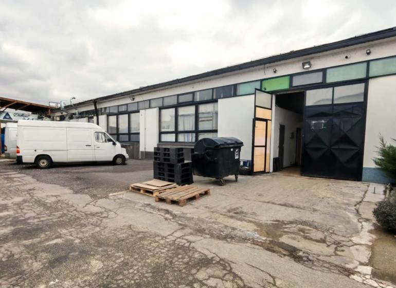 A building of warehouses and halls with cars in Trenčín, highlighted company advertisement in the foreground.