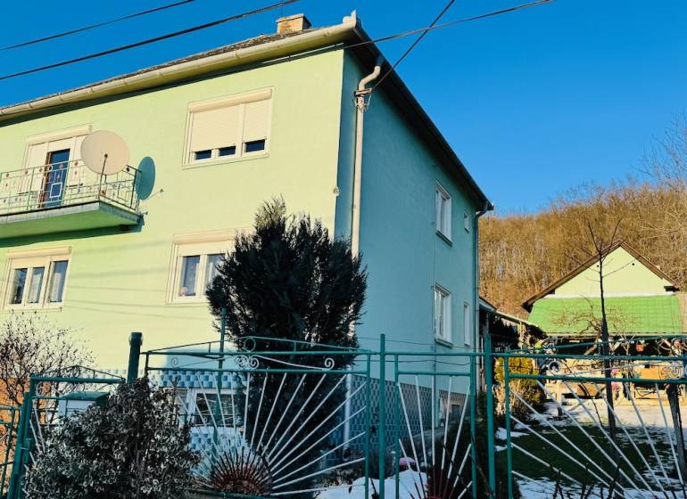 A family house in Horná Ves with a colorful facade and a garden, sunny day.