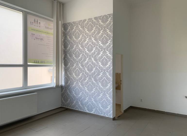 Offices with tiled floors and patterned wallpaper, light walls, radiator by the window.