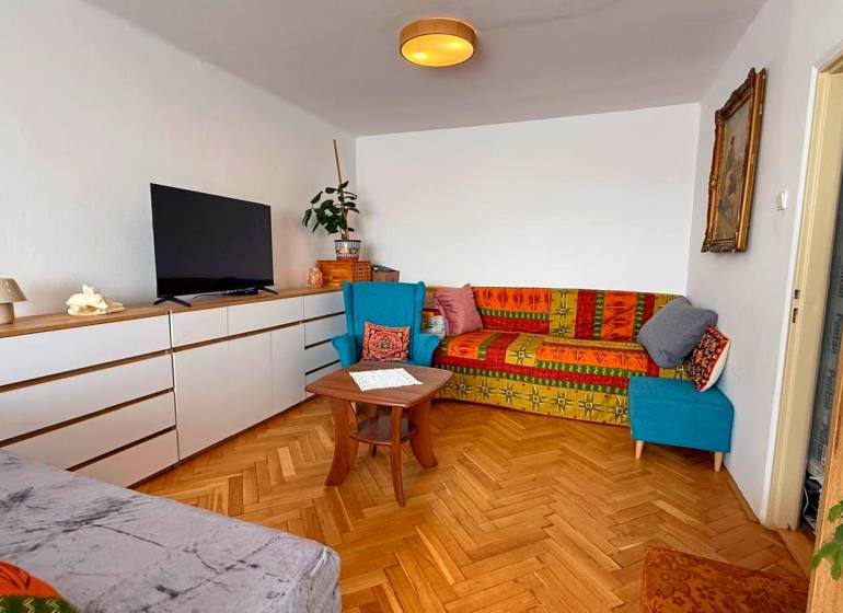 A living room in a 3-room apartment with a wooden decor floor and colorful sofas.