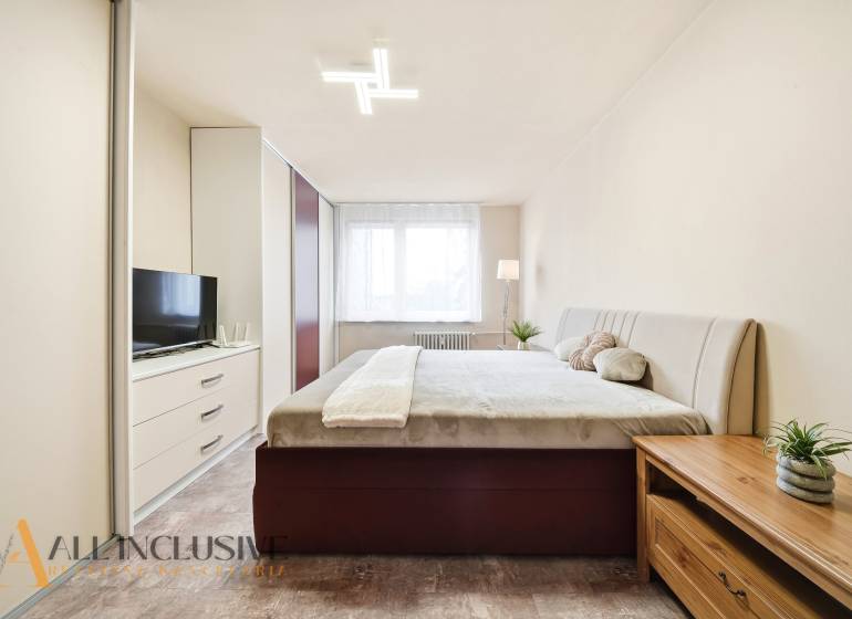 Bedroom in a 3-room apartment with a large bed, wardrobe, and floor with wooden decor.