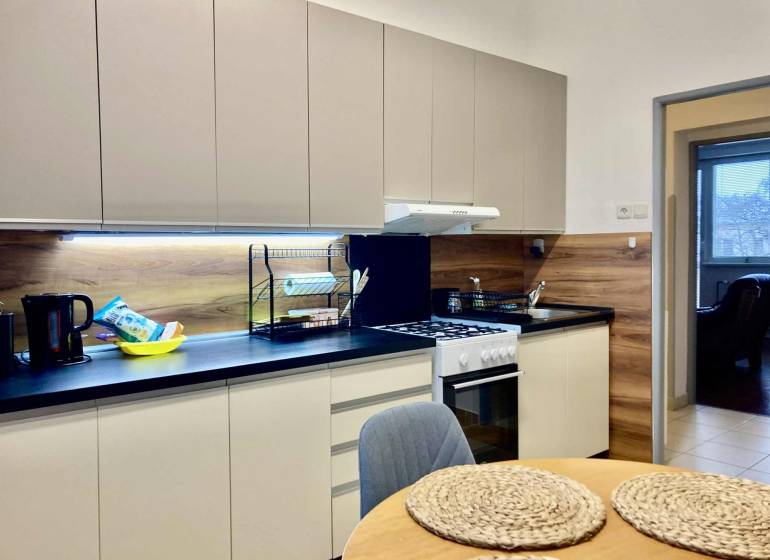 A kitchen in a 3-room apartment with a wooden decor floor and modern equipment.