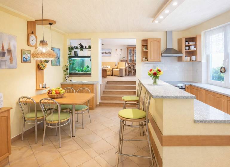 Kitchen and dining room with a bar in a family house, light shades and an aquarium.