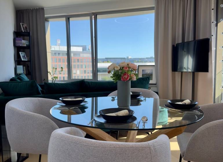 Dining area in a 3-room apartment with a round table and large windows.