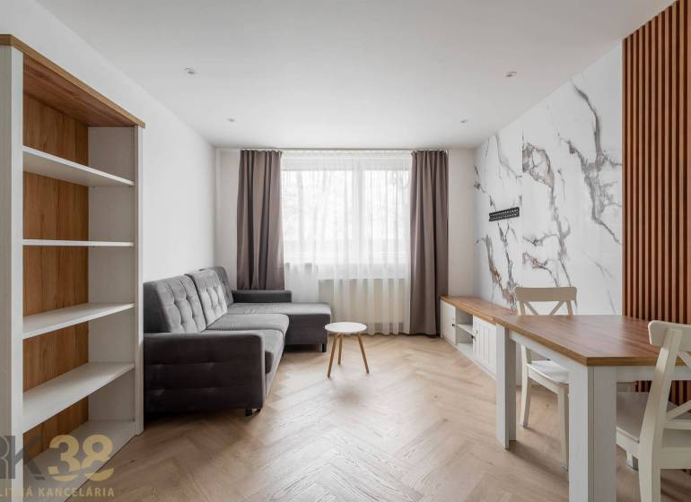 Living room in a 3-room apartment with a wooden decor floor and a gray sofa.