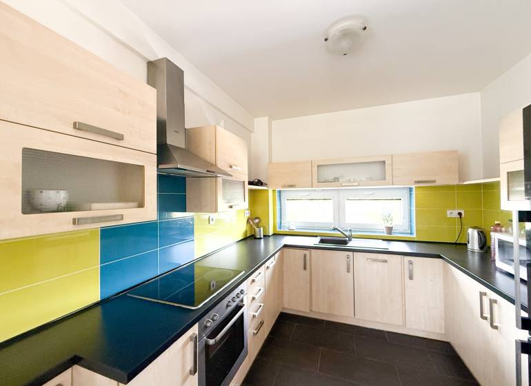 The kitchen of a 2-room apartment with colorful tiles and light cabinets.